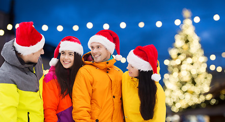 Image showing friends in santa hats and ski suits at christmas