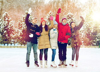 Image showing happy friends ice skating on rink outdoors