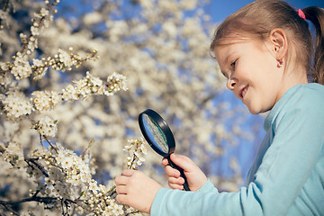 Image showing Happy little girl exploring nature with magnifying glass at the 