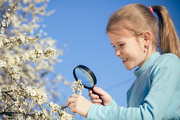 Image showing Happy little girl exploring nature with magnifying glass at the 