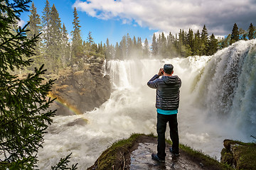 Image showing Nature photographer tourist with camera shoots while standing Ri