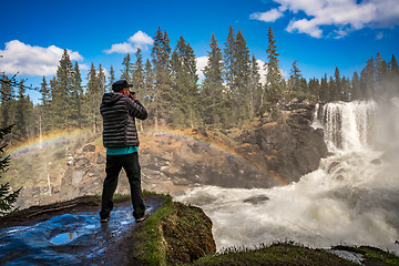 Image showing Nature photographer tourist with camera shoots while standing Ri