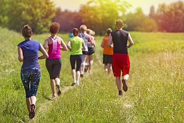 Image showing Group of young athlete running marathon outdoors in sunset