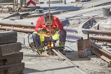 Image showing Worker with protective mask welding tram tracks in the city