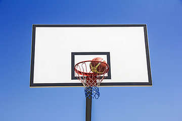 Image showing Basketball ball hit the basket in the blue sky background