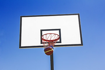 Image showing Basketball ball hit the basket in the blue sky background