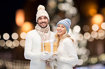 Image showing happy couple with christmas gift over night lights