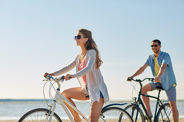 Image showing happy young couple riding bicycles at seaside