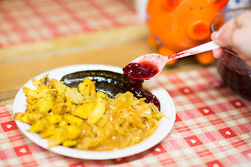 Image showing hand pouring sausages with cranberry sauce