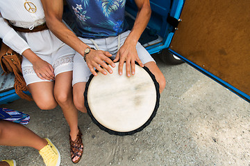 Image showing close up of hippie friends playing tom-tom drum