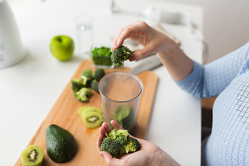 Image showing woman hand adding broccoli to measuring cup