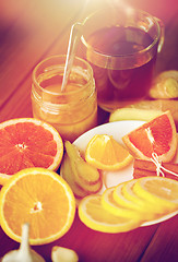 Image showing ginger tea with honey, citrus and garlic on wood