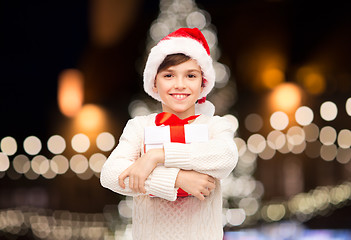 Image showing smiling happy boy in santa hat with christmas gift