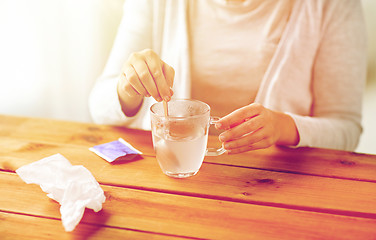 Image showing woman stirring medication in cup with spoon