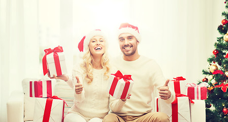 Image showing happy couple with christmas gifts and thumbs up