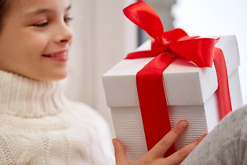 Image showing girl with christmas gift sitting on sill at home