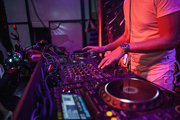 Image showing DJ playing music at mixer on colorful blurred background