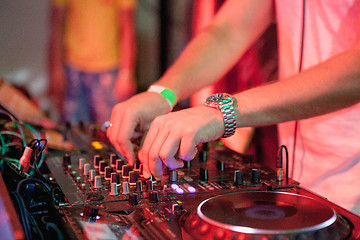 Image showing DJ playing music at mixer on colorful blurred background