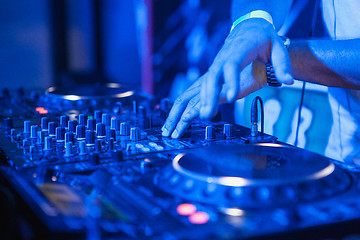 Image showing DJ playing music at mixer on colorful blurred background