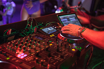 Image showing DJ playing music at mixer on colorful blurred background