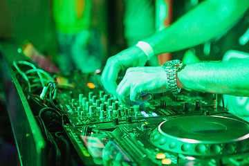 Image showing DJ playing music at mixer on colorful blurred background