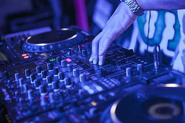 Image showing DJ playing music at mixer on colorful blurred background