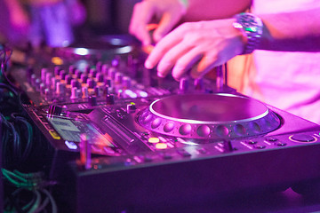 Image showing DJ playing music at mixer on colorful blurred background