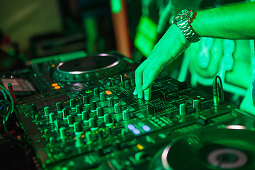 Image showing DJ playing music at mixer on colorful blurred background