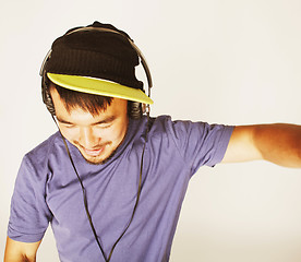 Image showing young asian man in hat and headphones listening music on white b