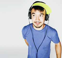 Image showing young asian man in hat and headphones listening music on white b