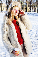 Image showing young pretty teenage hipster girl outdoor in winter snow park having fun drinking coffee, warming up happy smiling, lifestyle people concept