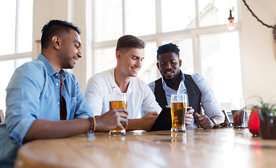 Image showing male friends with tablet pc drinking beer at bar