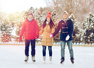 Image showing happy friends ice skating on rink outdoors