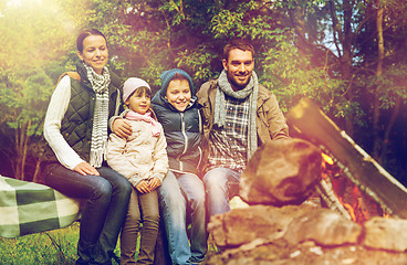 Image showing happy family sitting on bench at camp fire