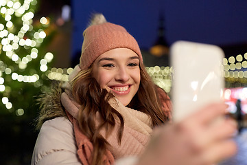 Image showing young woman taking selfie over christmas tree