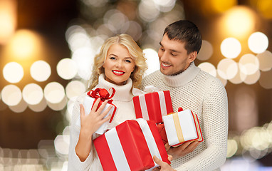 Image showing happy couple in sweaters holding christmas gifts