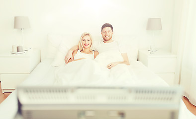 Image showing happy couple lying in bed at home and watching tv