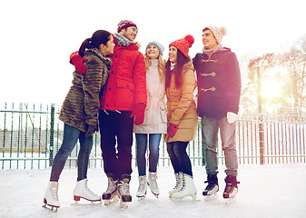 Image showing happy friends ice skating on rink outdoors