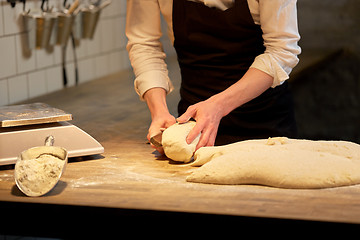 Image showing baker portioning dough with bench cutter at bakery