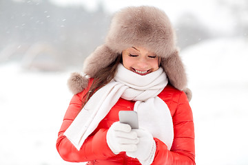 Image showing happy woman in winter fur hat with smartphone