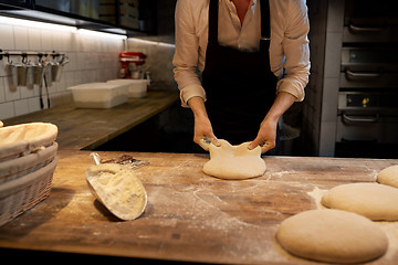 Image showing baker portioning dough with bench cutter at bakery