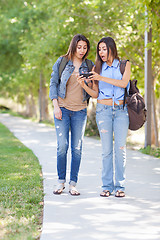 Image showing Two Beautiful Young Ethnic Twin Sisters With Backpacks Using A S