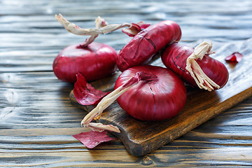 Image showing Sweet red onions on an old wooden board.