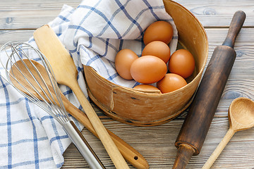 Image showing Kitchen utensils and brown eggs in an old sieve.