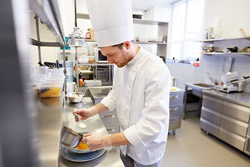 Image showing happy male chef cooking food at restaurant kitchen