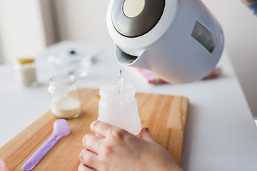 Image showing hands with kettle and bottle making baby milk