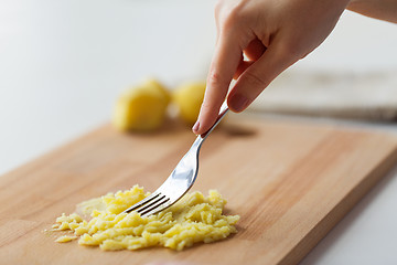 Image showing hand with fork making mashed potato on board