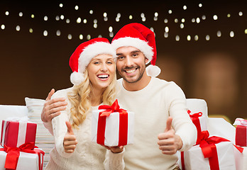 Image showing happy couple with christmas gifts and thumbs up