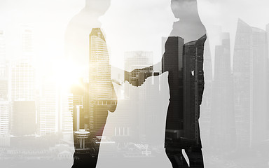 Image showing business people shaking hands over city background