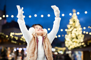 Image showing happy girl wearing earmuffs over christmas lights